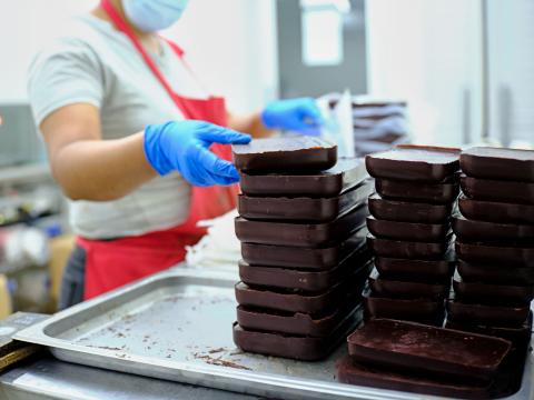 Tes tablettes de chocolat empilées par une personne portant des gants